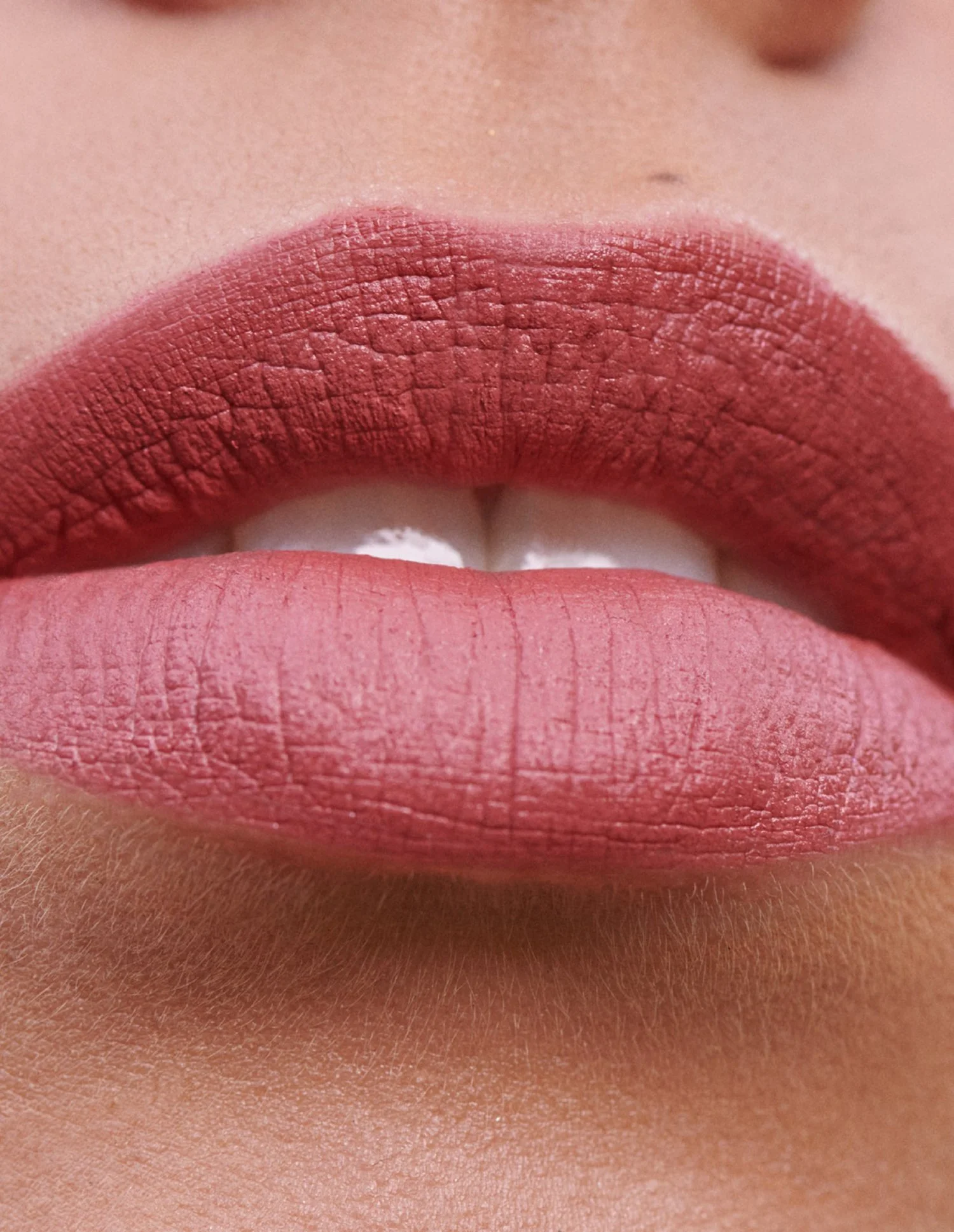 Close-up of lips with pink lipstick, showing detailed texture and skin surrounding the mouth.