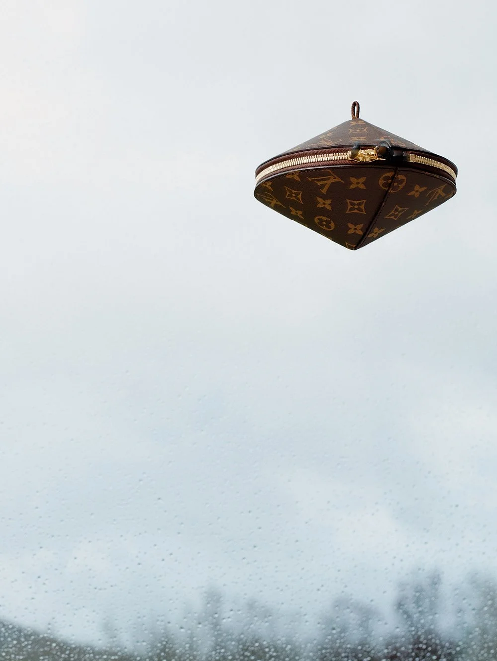 Ein Louis Vuitton Geldbeutel schwebt in der Luft vor einem regnerischen Himmel.
