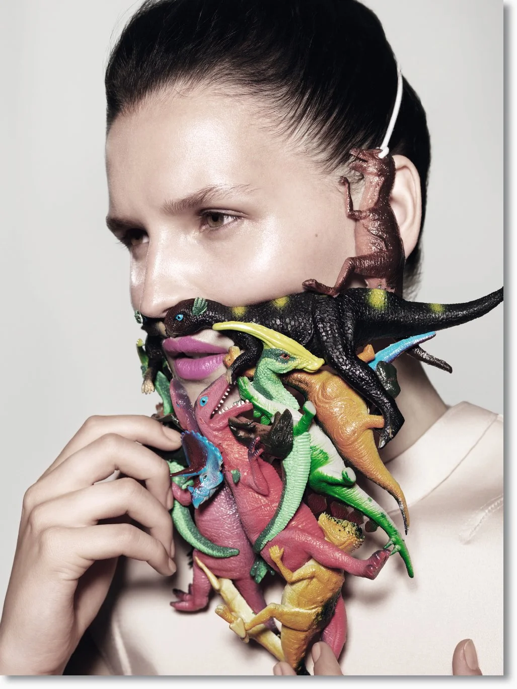 Eine Frau mit dunklen Haaren, die bunte Kunststoffmodelle von Dinosauriern um ihren Hals trägt.