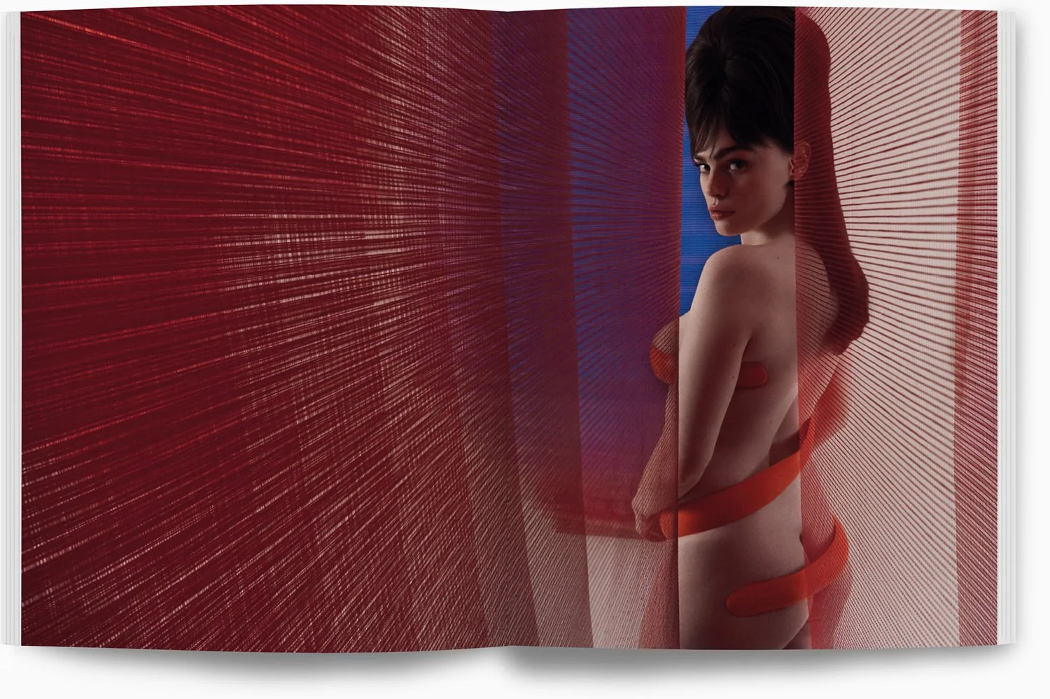 Eine Frau steht aufrecht und blickt zur Seite, umgeben von roten, transparenten Stoffbahnen, die sich im Raum ausbreiten und eine künstlerische, moderne Atmosphäre schaffen.