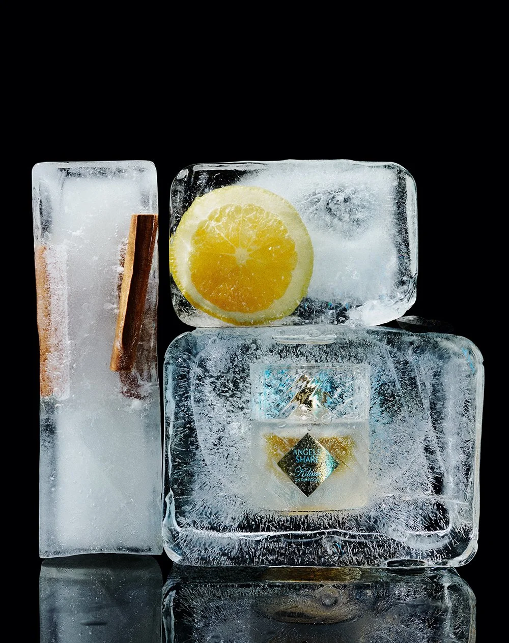 Eiswürfel mit Zitronenscheibe, Zimtstange und einem Parfüm im Eis