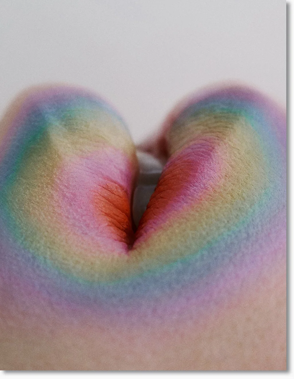 Nahaufnahme von einem bunten, babyfarbenen Kinderhände, die in Herzform zusammengestellt sind.