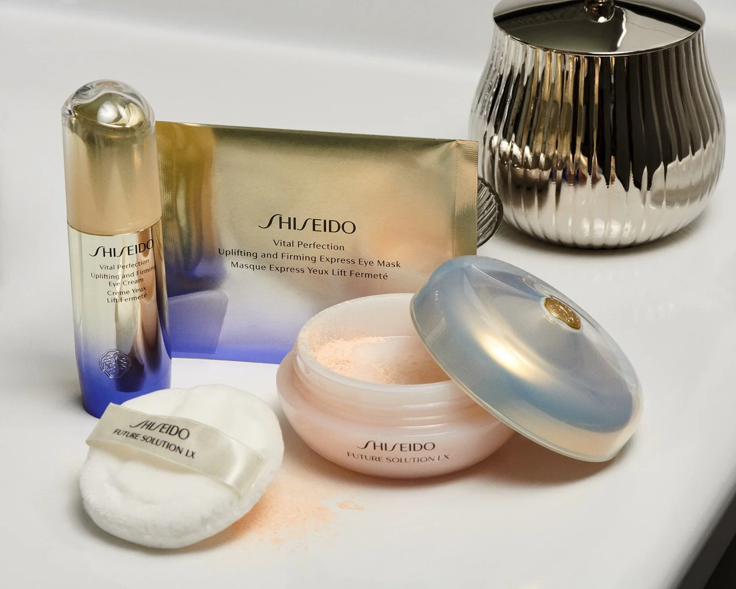 Shiseido skincare products including cream, facial mask, cotton pad, and a silver decorative item on a white surface.
