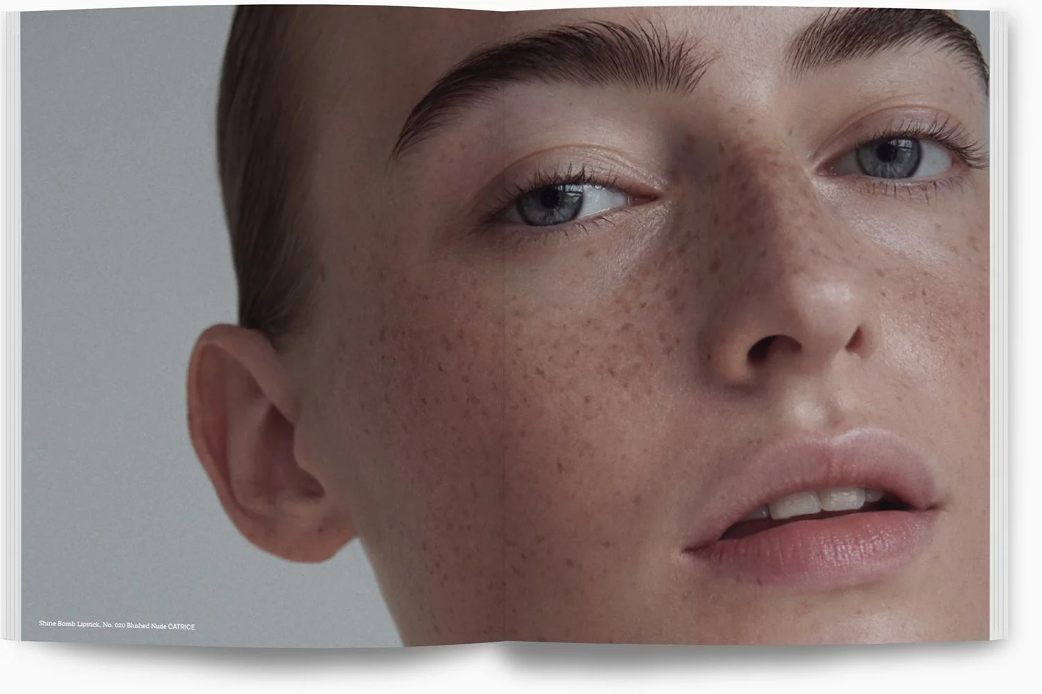 Nahaufnahme eines Gesichts mit blauer Augen, sommersprossiger Haut und kurzen braunen Haaren.