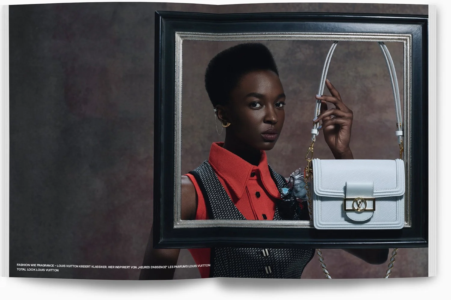 Eine schwarze Frau hält eine weiße Handtasche in einem Rahmen vor ihrem Gesicht, im Hintergrund ein dunkler, unscharfer Hintergrund.