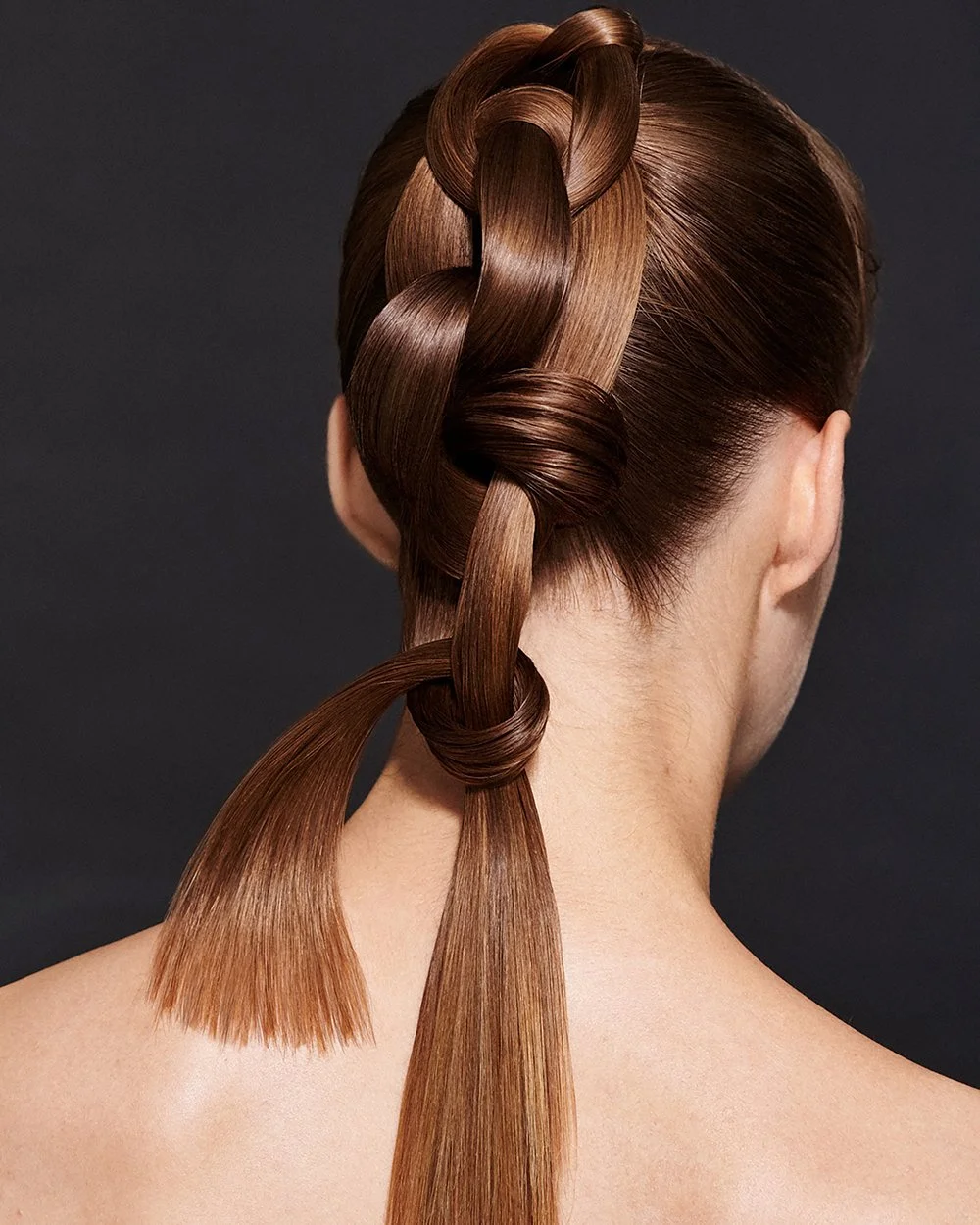 Frisiertem, glattes, braunes Haar in einem kunstvollen Zopf und Knoten auf einem schwarzen Hintergrund.