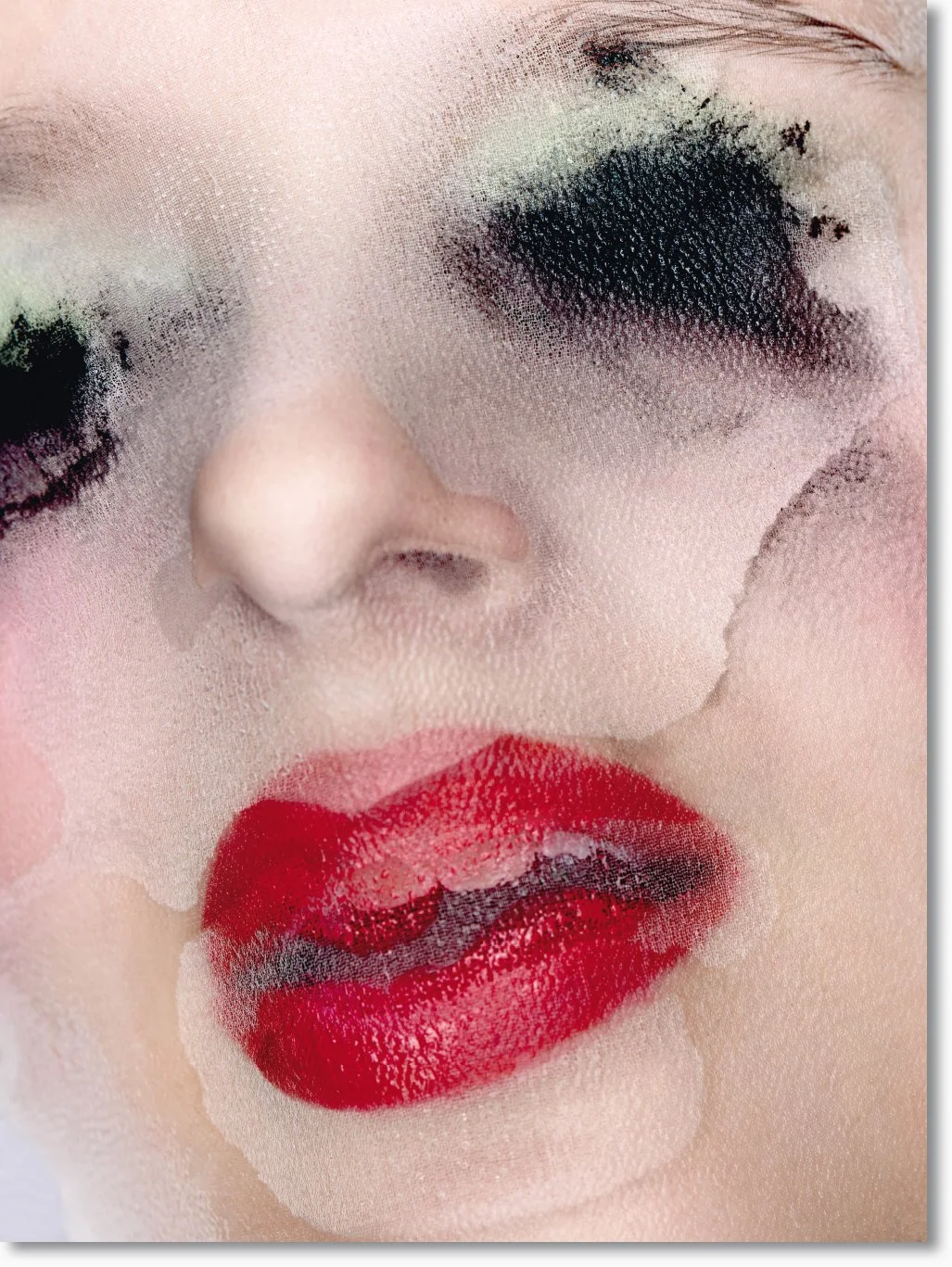 Nahaufnahme eines Gesichts mit geschminkten roten Lippen, schwarze Lidschatten und geschlossene Augen, der Eindruck eines fotografischen Effekts.