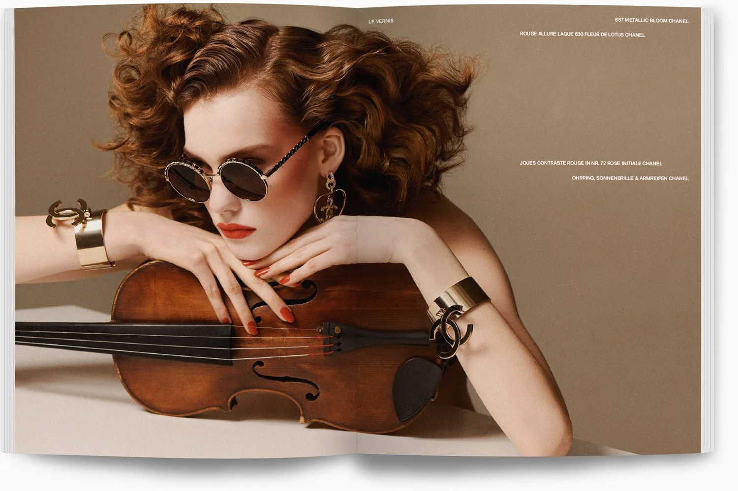 Eine Frau mit roten Locken, dunklen Sonnenbrillen, rotem Lippenstift und Goldschmuck, die ein Klavier hält und darauf lehnt.