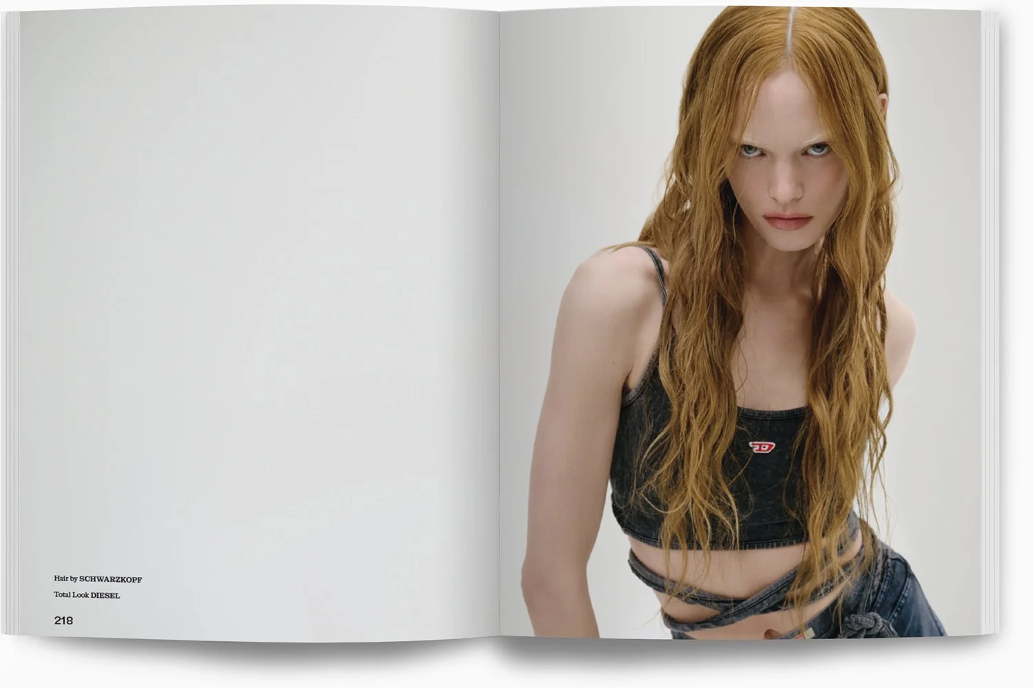 Fotografie eines jungen Mädchens mit langen, roten, lockigen Haaren, die einen schwarzen Top trägt, in einem minimalistischen Studio mit weißem Hintergrund.