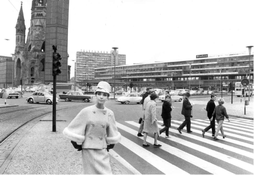 Historische schwarz-weiße Fotografie von einem Crosswalk in Berlin mit Frauen und Männern in 1960er-Jahre Kleidung, im Hintergrund moderne Gebäude und der Fernsehturm
