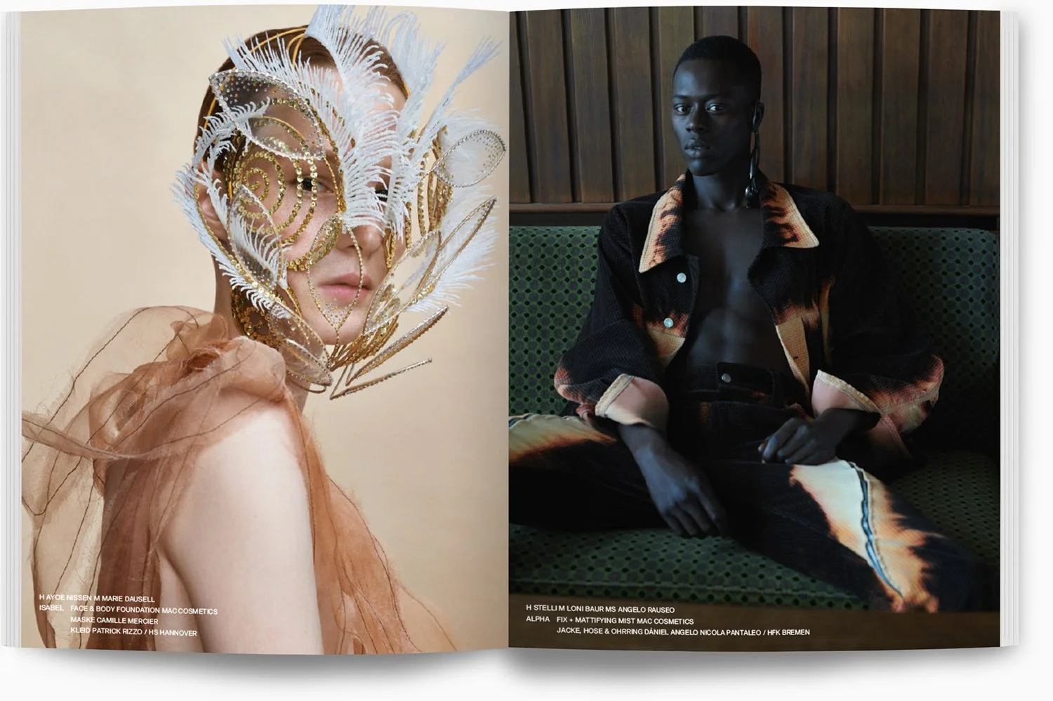 Zwei modellhafte Menschen in einem Magazin. Die Person auf der linken Seite trägt eine große, dekorative Maske aus Federn und Goldschmuck, während die rechte Person auf einem grünen Sitz sitzt, dunkle Haut hat, kurze Haare, eine offene Jacke mit Must