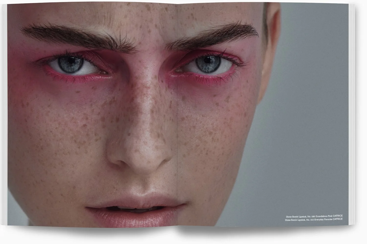 Nahaufnahme eines Gesichts mit blauen Augen, roten Augenlidern, Sommersprossen und geändertem Make-up um die Augen