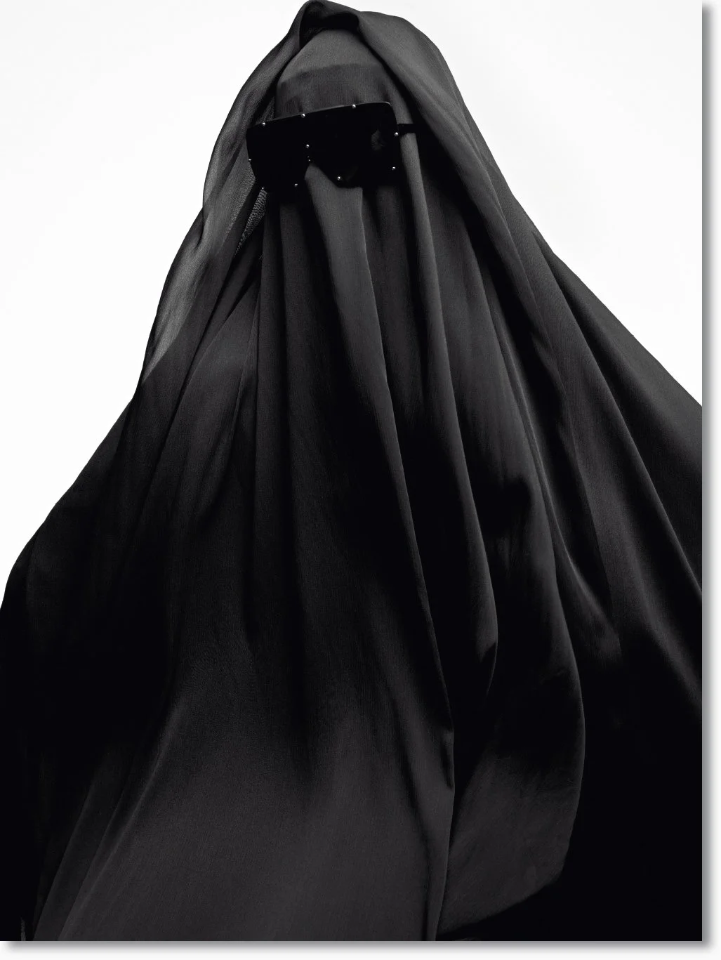 Eine Person, die einen schwarzen Schleier trägt, der das Gesicht vollständig verdeckt, mit einer schwarzen Sonnenbrille darüber.