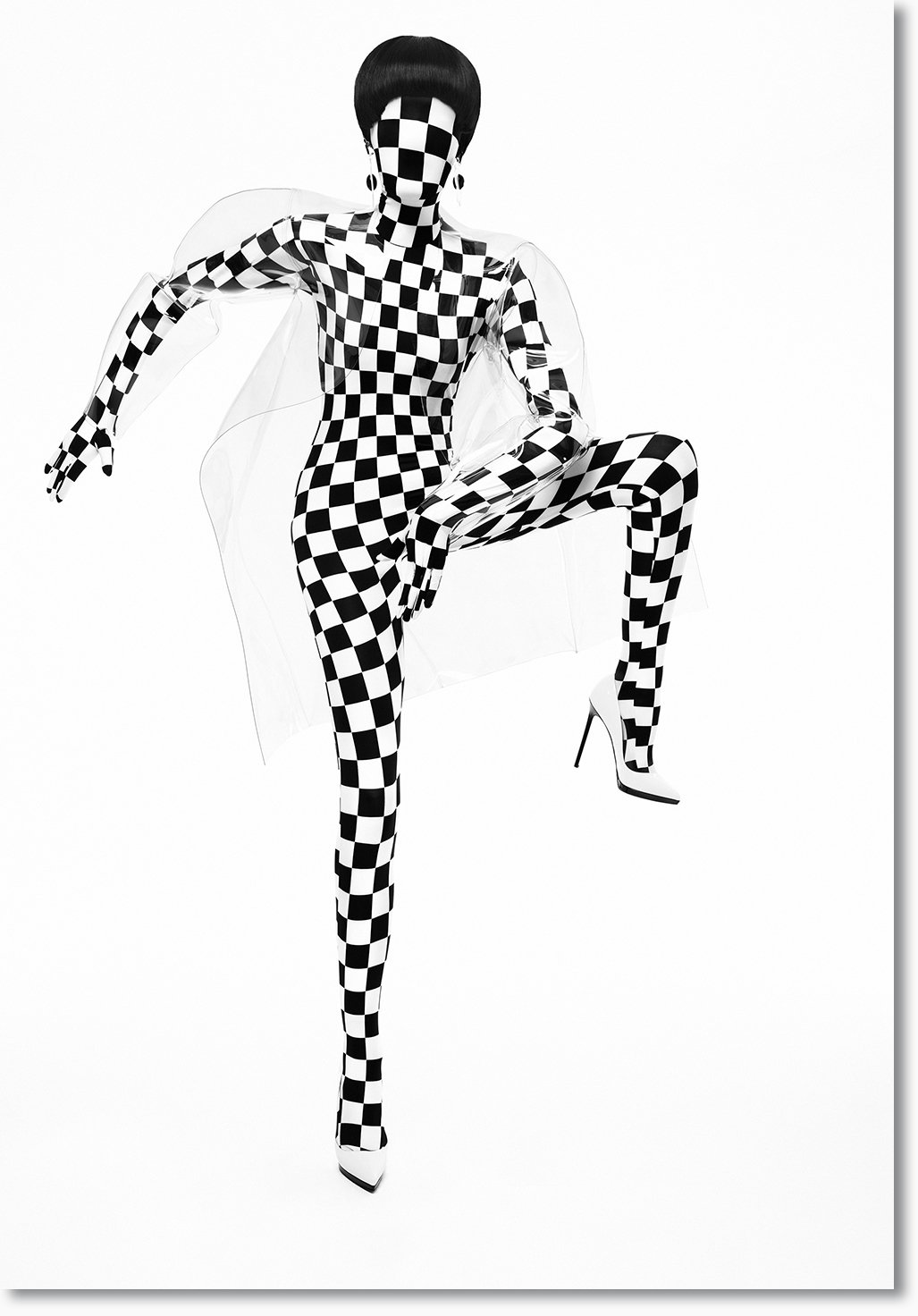 Eine Person trägt ein schwarz-weiß kariertes Kleid, Stiefel und trägt einen karierten Gesichtscode, mit kurzer schwarzen Frisur und großen Ohrringen.