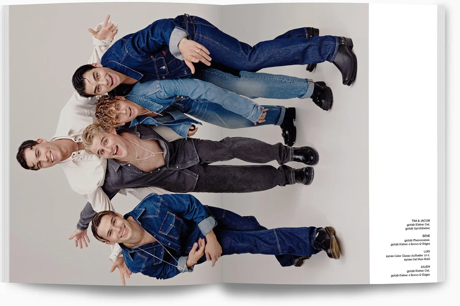 Fünf junge Menschen stehen eng zusammen vor weißem Hintergrund, lachen und posieren für die Kamera in modernen, lässigen Outfits.