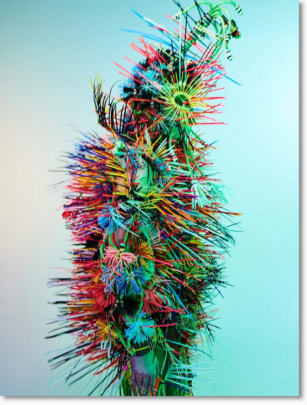 Ein kunstvolles, farbenfrohes Arrangement aus vielen bunten Plastikstäbchen und -spiralen, das ein abstraktes, organisches Design bildet.