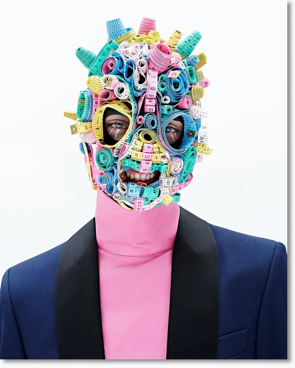 Porträt eines Menschen mit einem Gesicht, das vollständig aus bunten, zusammengerollten Maßbändern besteht, die die Gesichtszüge formen.