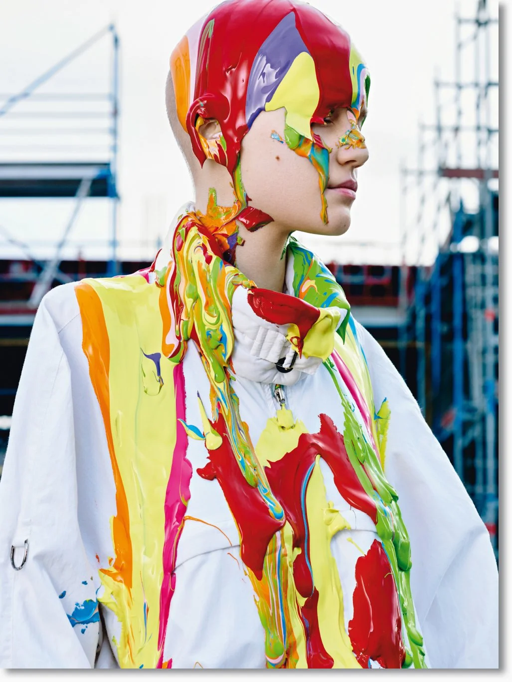 Ein Mädchen mit weißem Jacke, an der das Gesicht, Teile des Hemdes und das Haar mit bunter Farbe bedeckt sind.