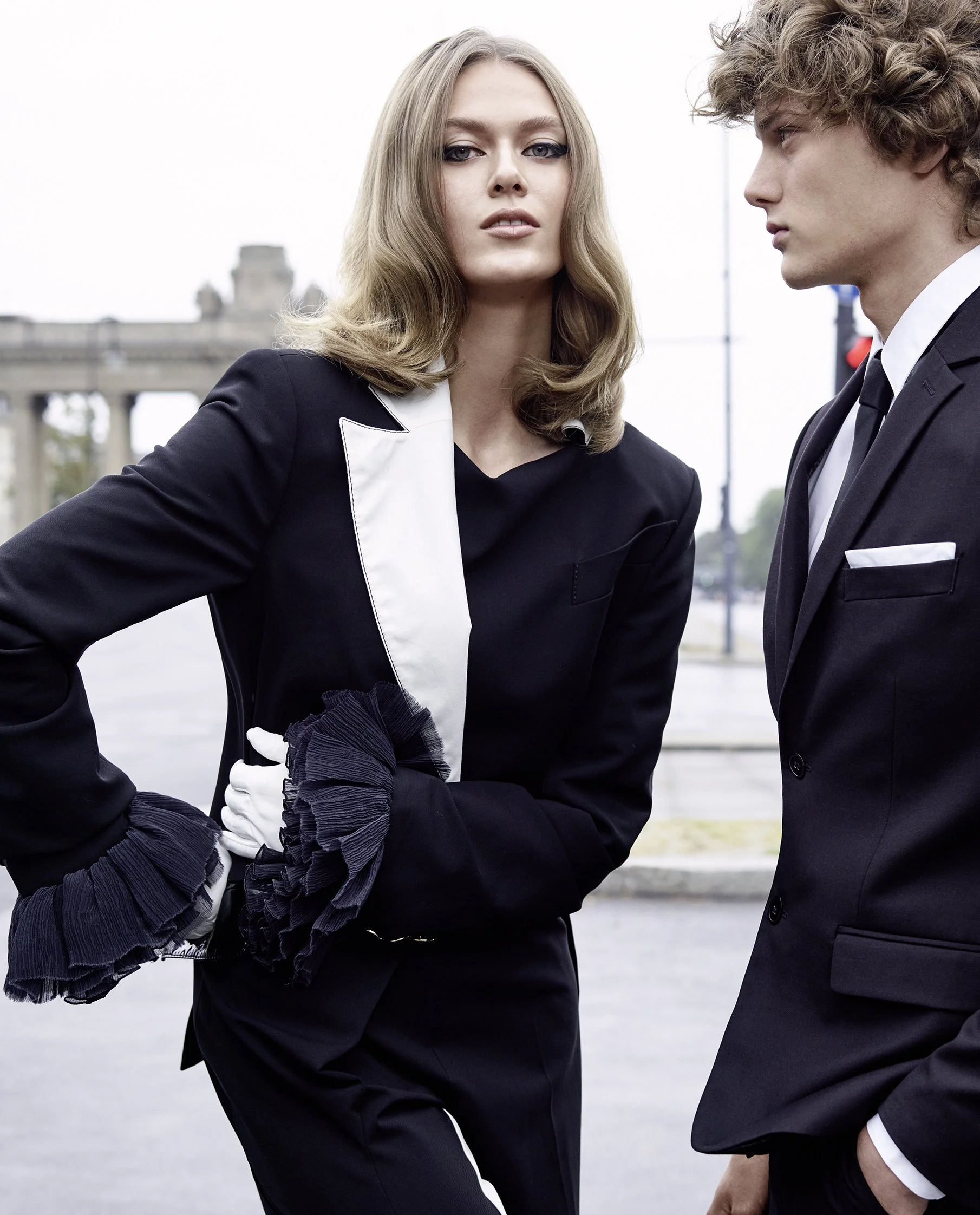 Zwei junge Menschen in eleganter Kleidung stehen draußen.