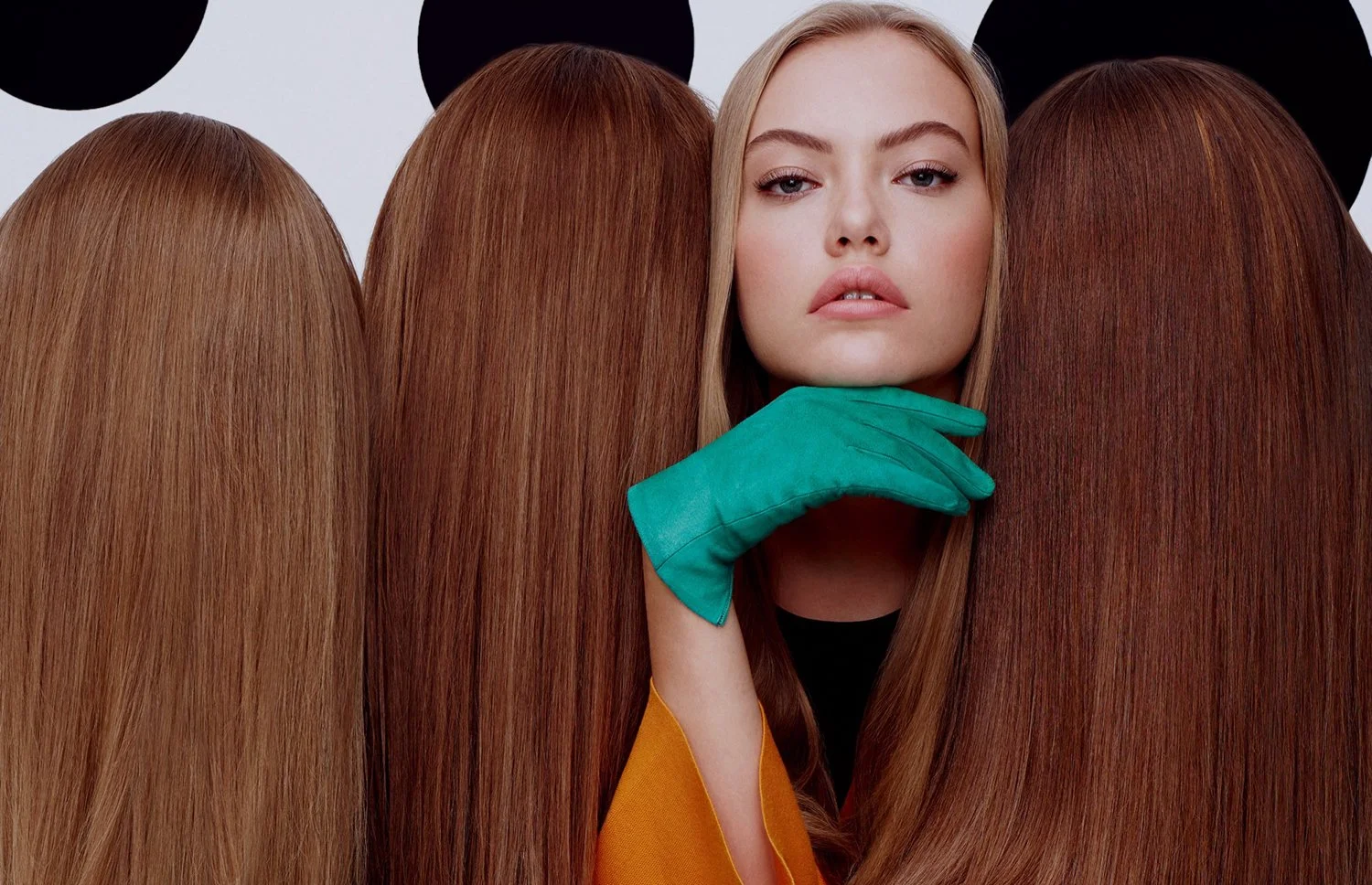 A woman with blonde hair and natural makeup surrounded by several red-haired women, with one woman in the center wearing a teal glove and an orange sleeve, and black background with black polka dots.