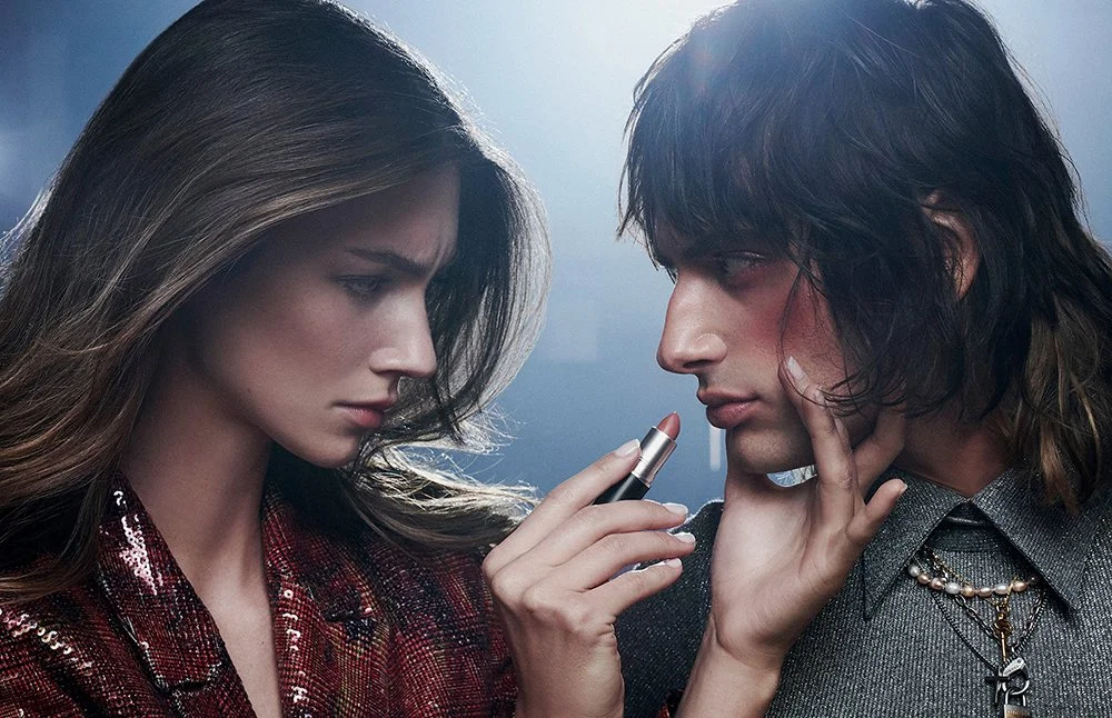 Ein Mann und eine Frau nähern sich sehr nahe, die Frau hält einen Lippenstift und sieht den Mann an.