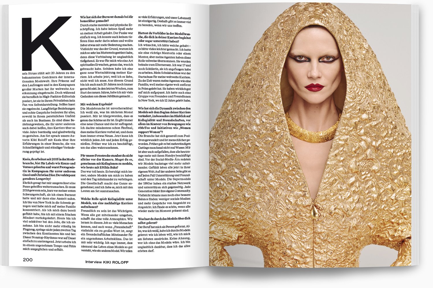 Ein Magazin-Layout mit einem Interview auf der linken Seite und einem Porträt einer Frau auf der rechten Seite. Die Frau trägt ein goldfarbenes, bauchbedeckendes Oberteil mit einer passenden Kette und einem goldenen Schleier, der ihr Haar bedeckt, so