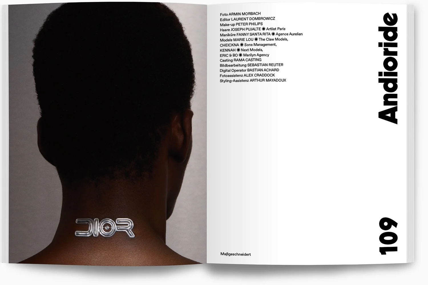 Rückansicht eines schwarzen Menschen mit kurzer, lockiger Frisur, ein silberner Schmuck in Form eines stilisierten Quaders befindet sich am Nacken. Die rechte Seite des Bildes ist ein weißes Booklet mit schwarzen Texten, darunter die Überschrift "And