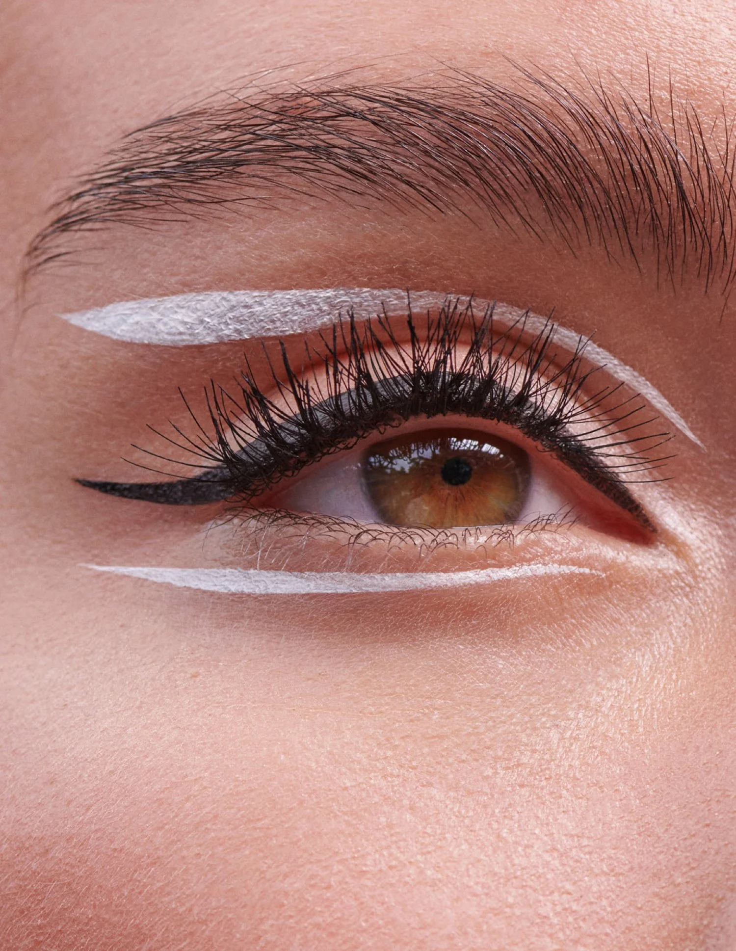 Close-up of a person's eye with artistic white eyeliner and black winged eyeliner design.