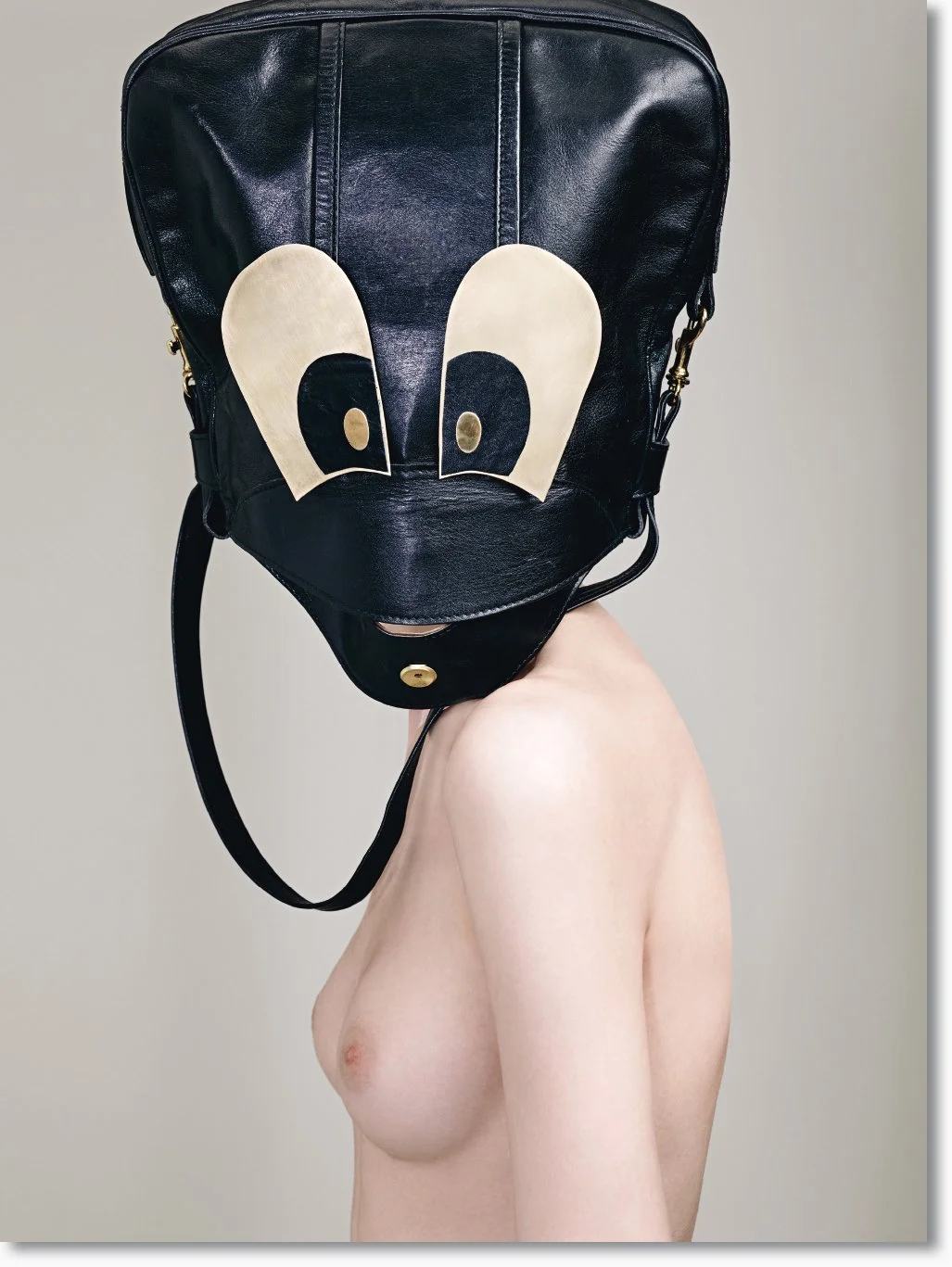 Nackte Person mit Rucksack, der das Gesicht verdeckt, auf einem neutralen Hintergrund.