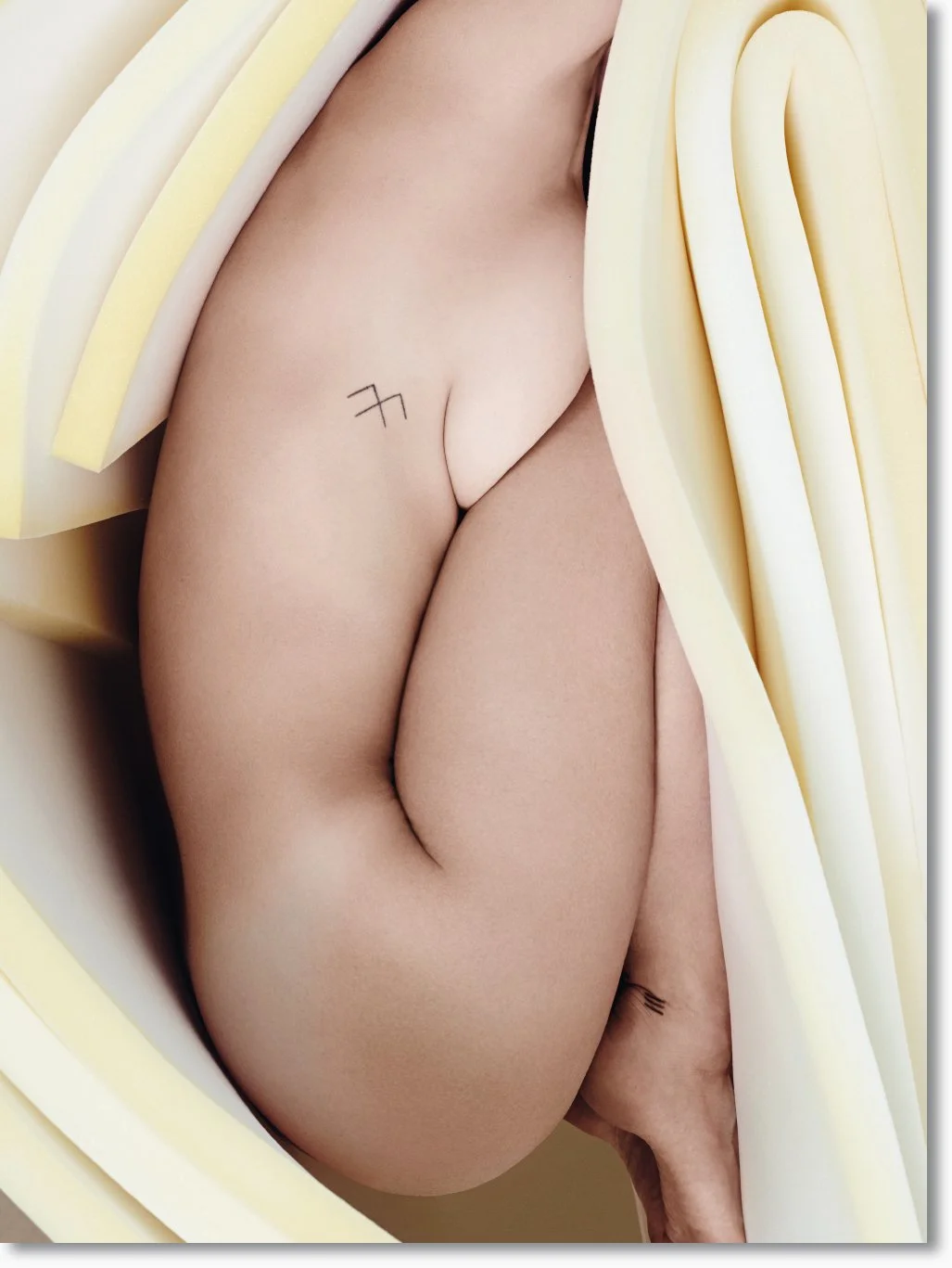 Nahaufnahme eines Menschen mit Tattoo auf dem Oberschenkel, umgeben von Nahrungsmitteln, die wie Käse aussehen.