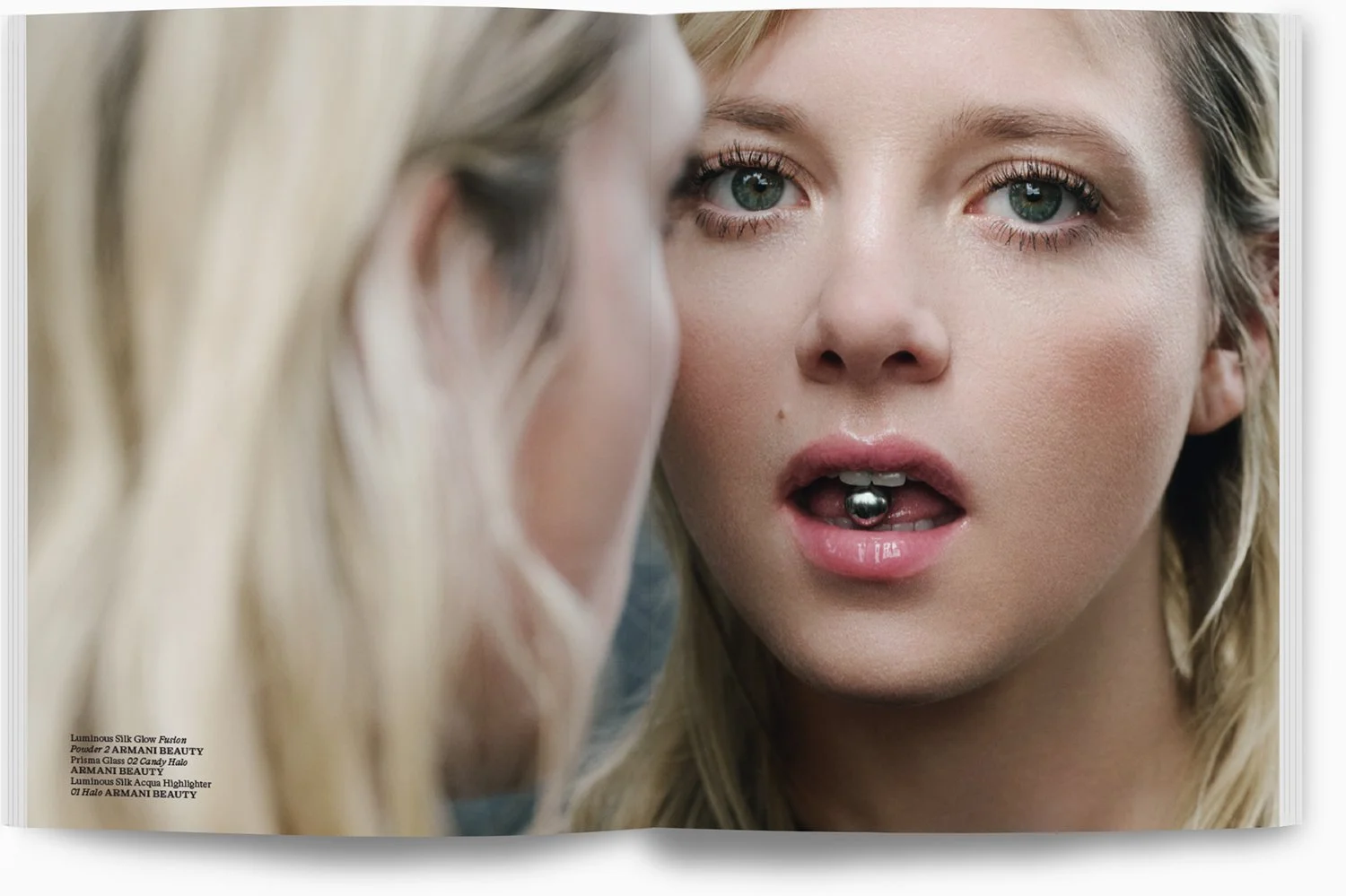 Nahaufnahme eines Mädchens, das vor einem Spiegel steht, mit sichtbarem Lippenpiercing, ein Make-up-Produkt in der Nähe des Mundes, Blick in den Spiegel, blaue Augen, lange blonde Haare.