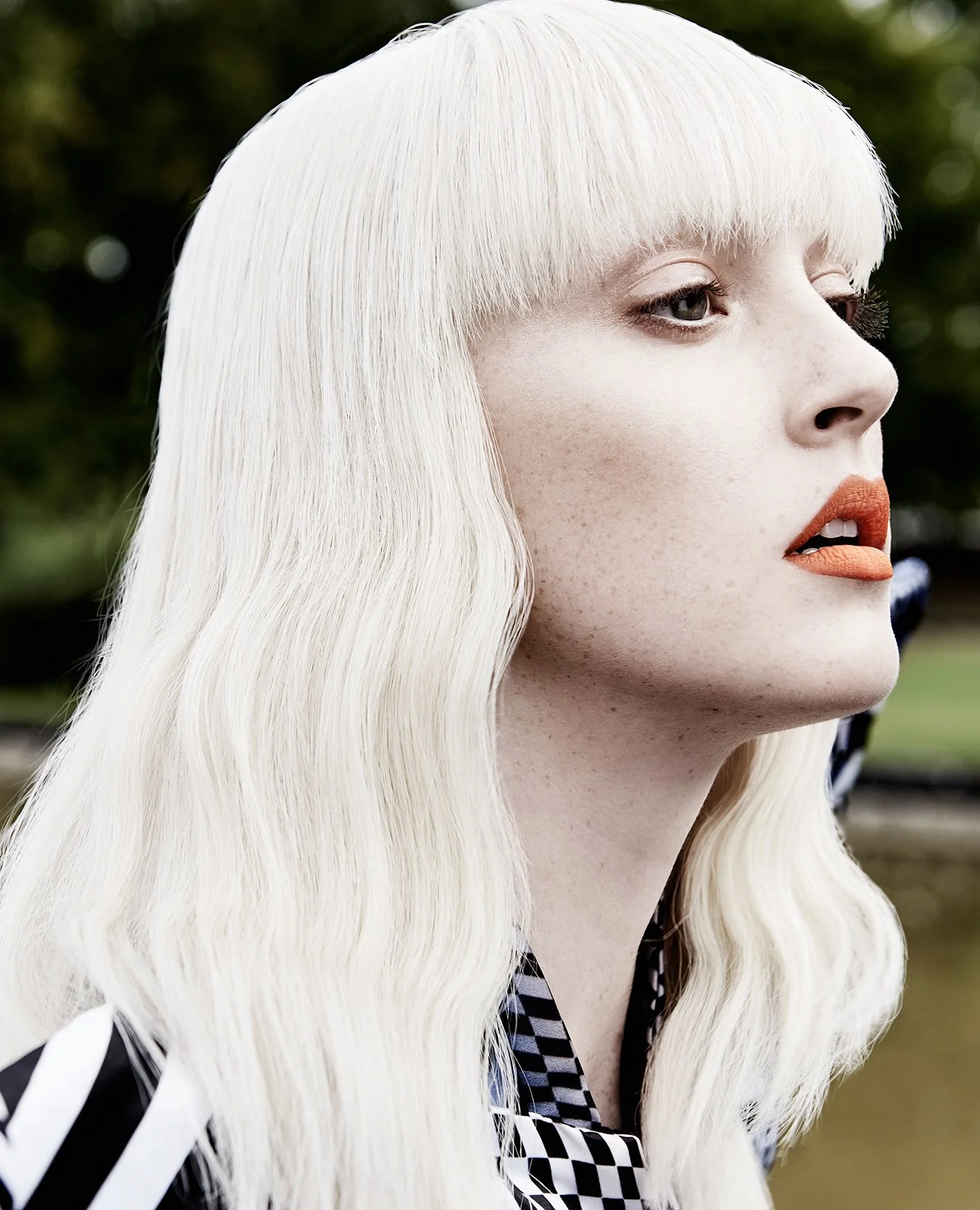 Nahaufnahme eines Mädchens mit platinumblondem, welligem Haar, roten Lippen und dunklen Augen.