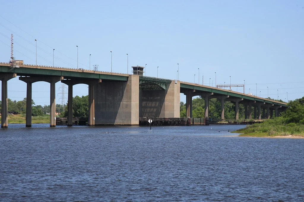 A large bridge over a body of water on a clear day with trees in the background.