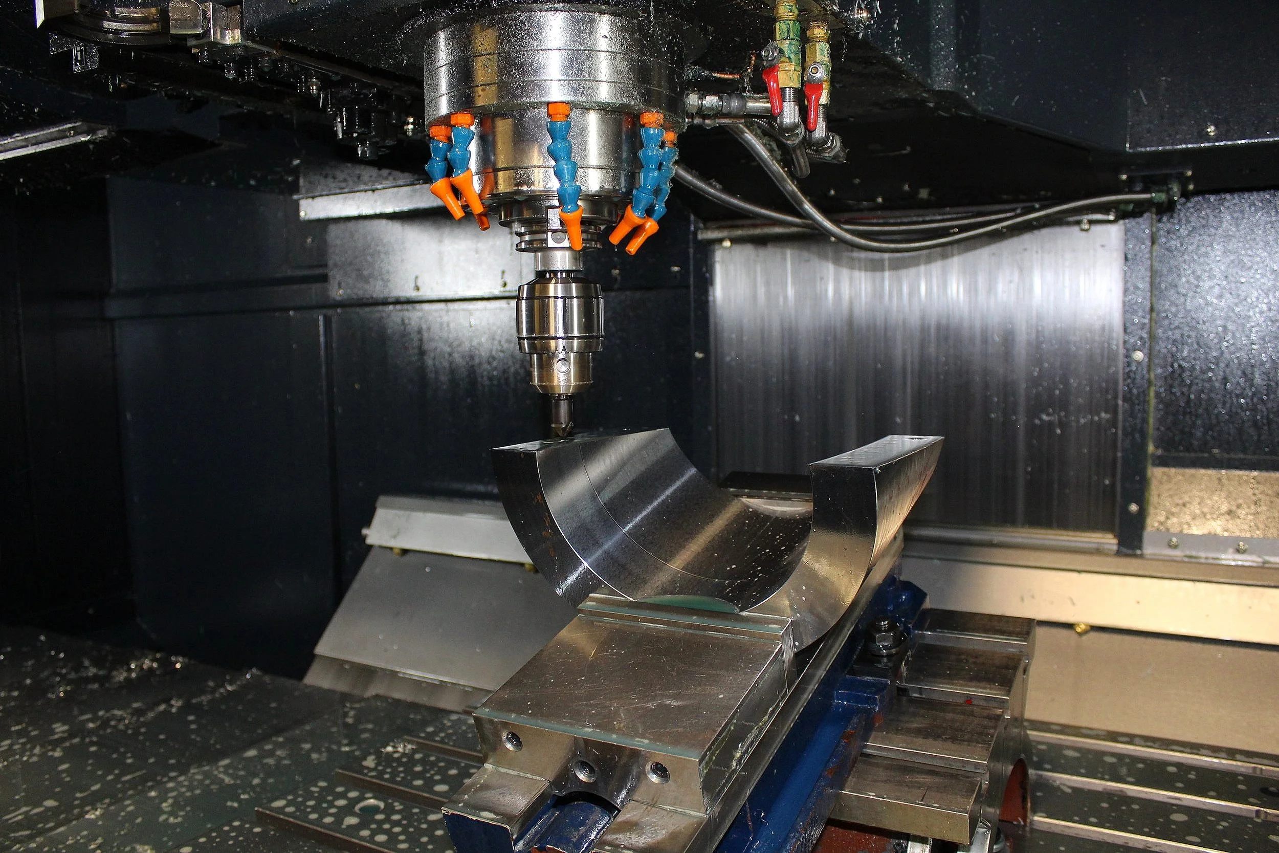 Close-up of a CNC machine carving a metallic component with a rotating drill.