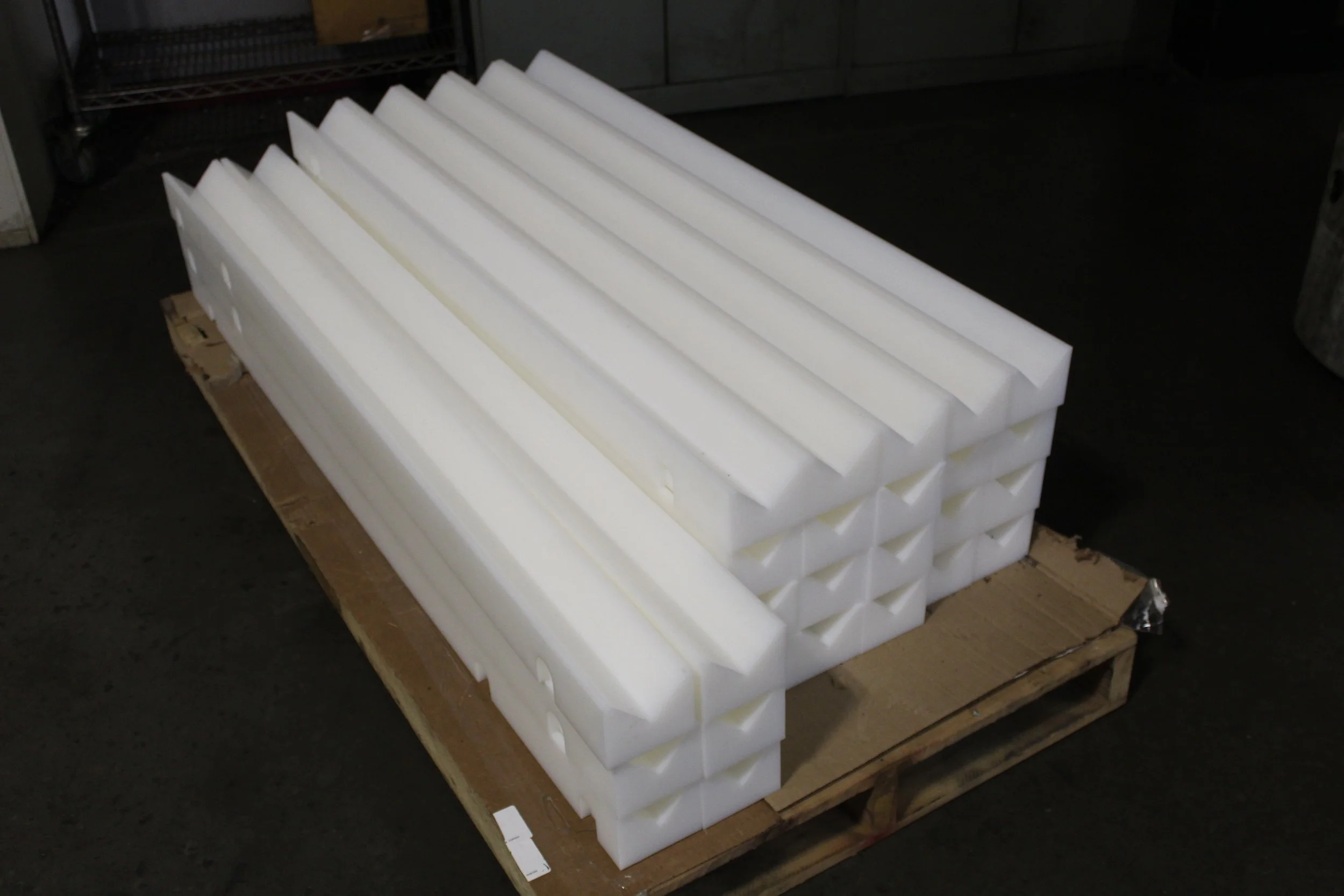 Stack of white foam packing materials on a wooden pallet in a warehouse.