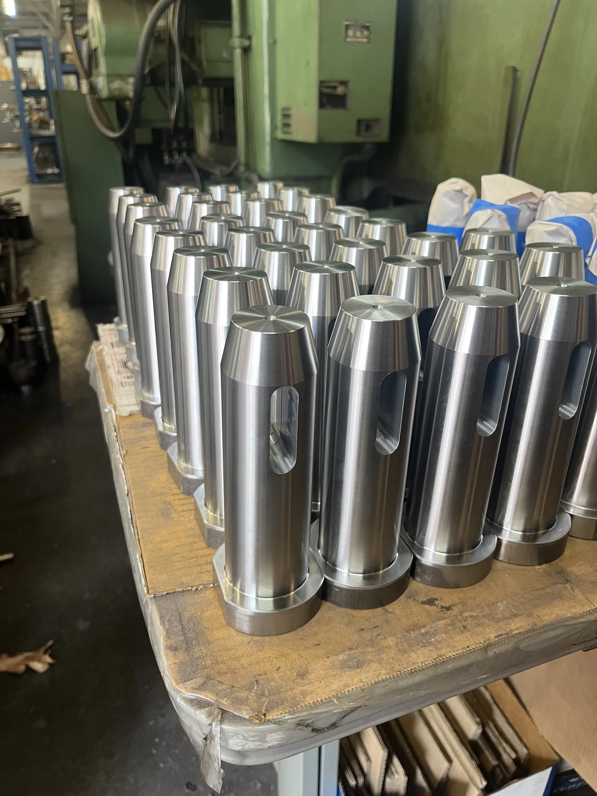 Multiple stainless steel conical objects on a wooden workbench in an industrial setting.