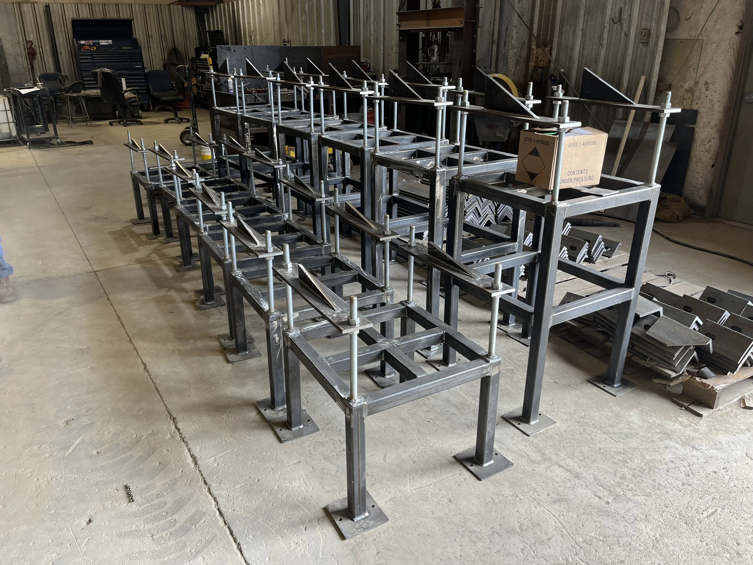 Metal scaffolding structure with multiple levels and angled platforms inside a workshop or warehouse.