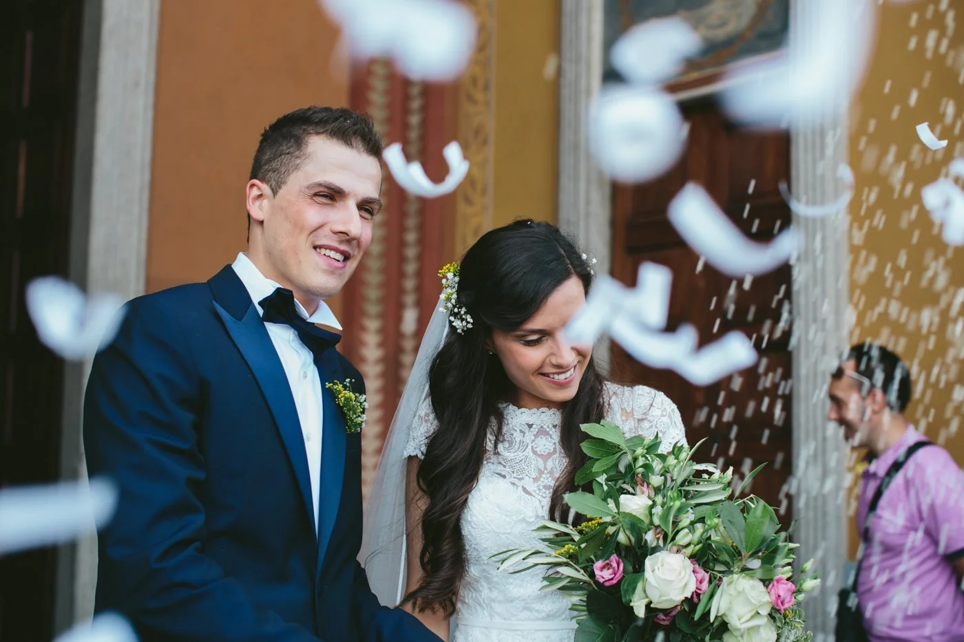 Sposi di sposi sorridenti con bouquet durante il loro matrimonio, con coriandoli che cadono.