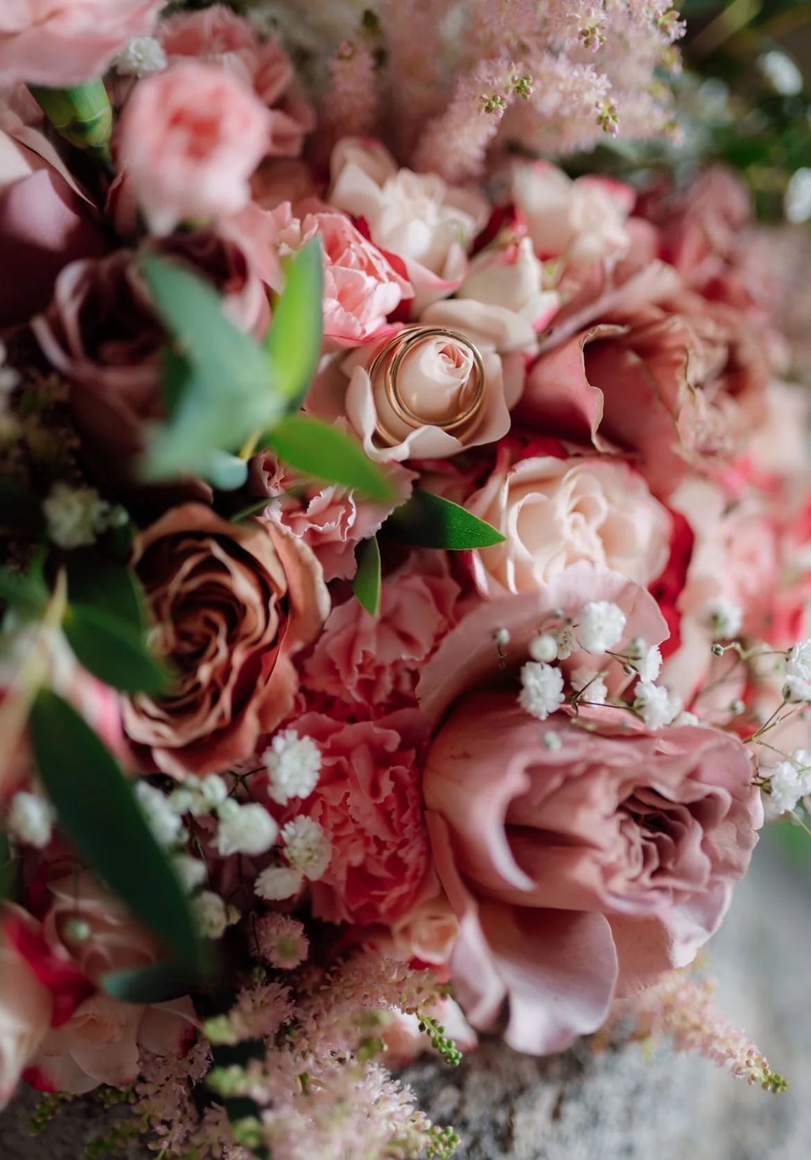 Bouquet di fiori rosa con alcune fedi nuziali posizionate tra i fiori.