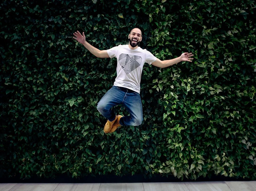 a man with high energy jumping in front of a vine wall at the culture cove retreat space