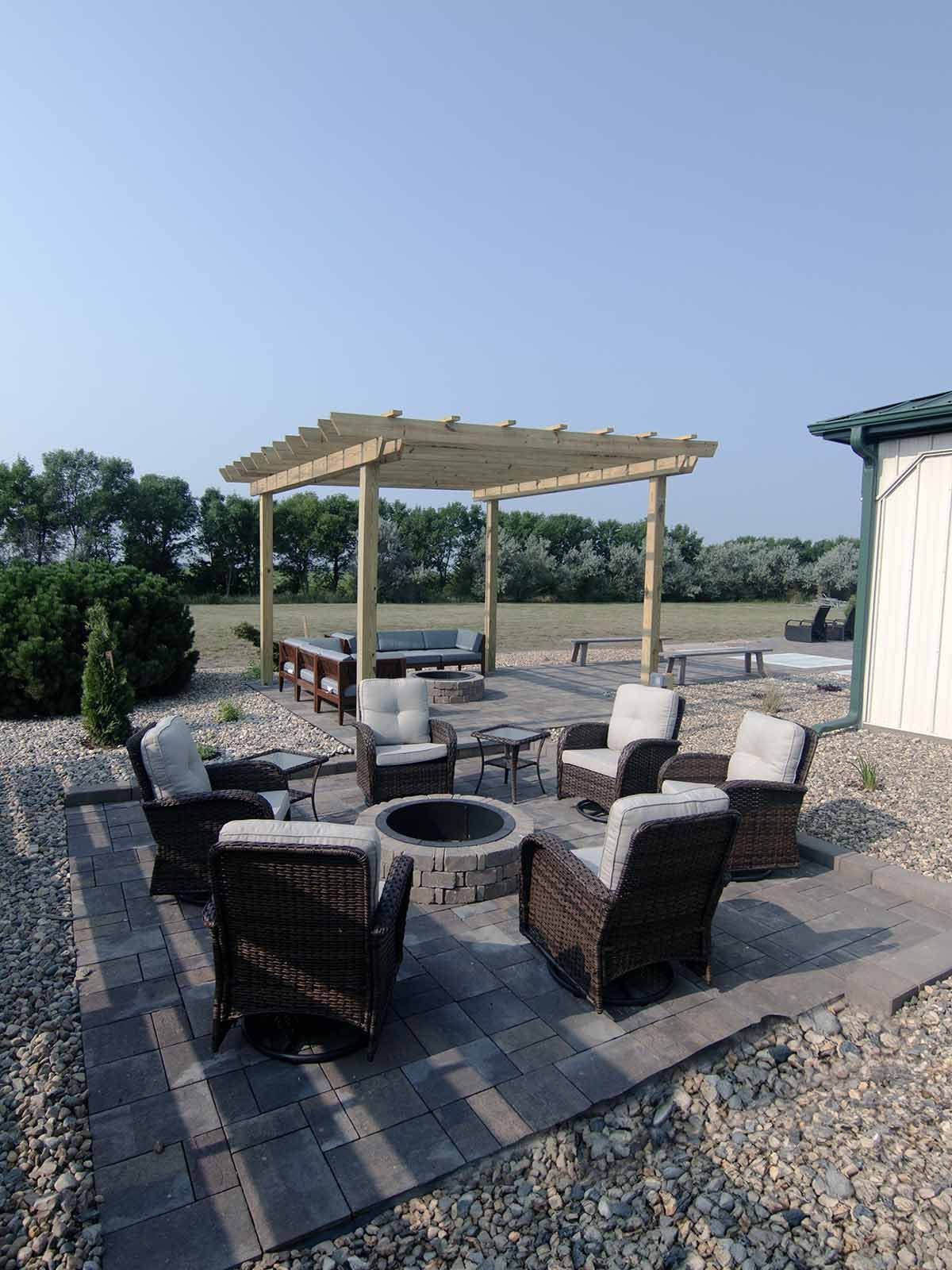 Inviting patio space featuring cozy outdoor furniture arranged around a fireplace. The charming pergola is perfect for relaxing or gathering with friends.