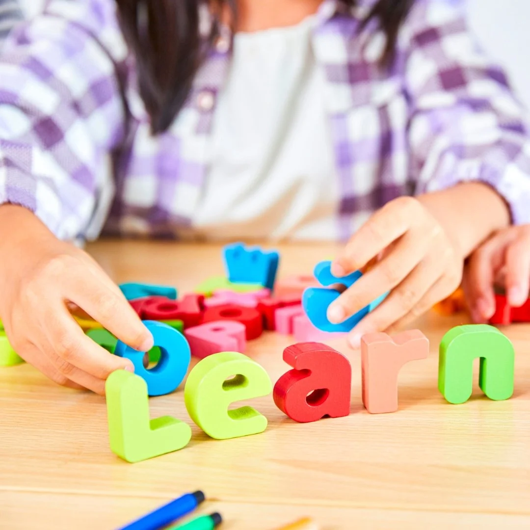 Toddler spelling "Learn" with blocks
