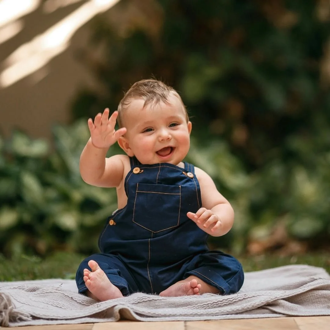 Baby boy waving and smiling.