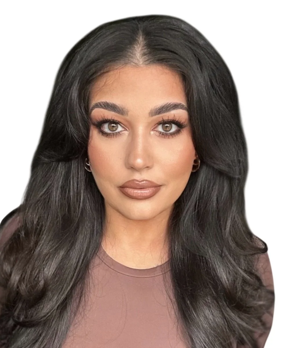 A woman with long black wavy hair, light makeup, a nose piercing, and wearing a red top, smiling at the camera.