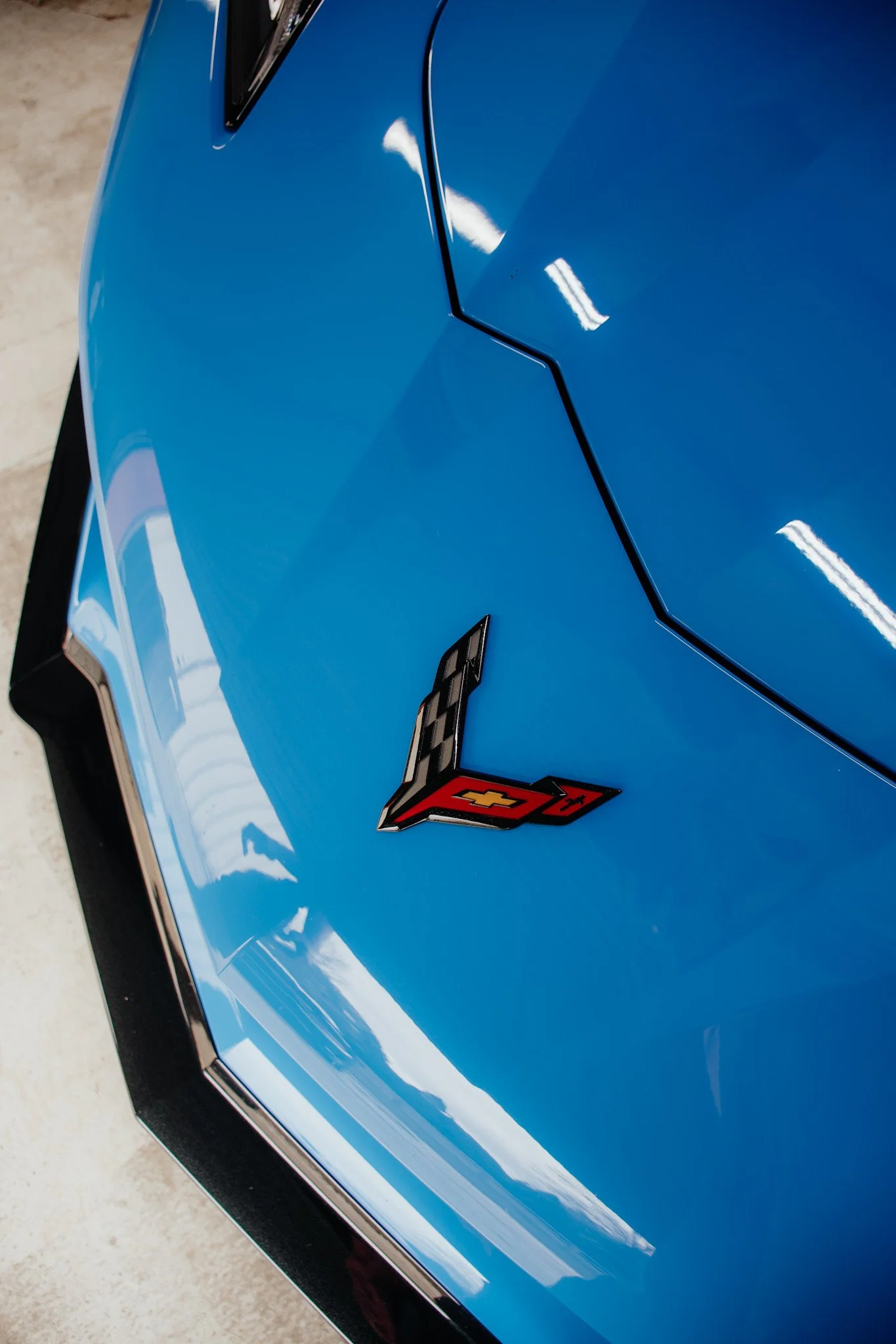 Close-up of a blue Chevrolet Corvette car hood with a V8 emblem.