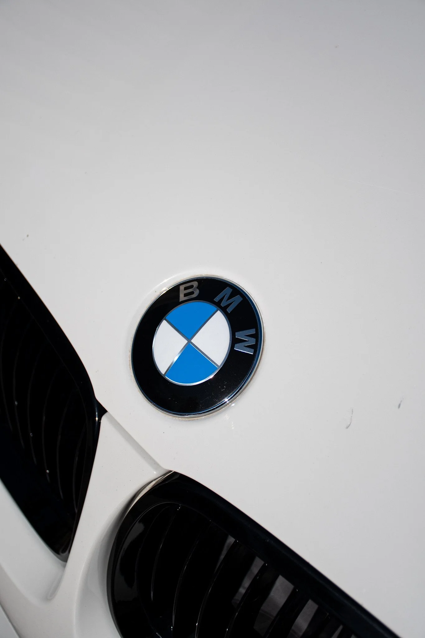 Close-up of a white BMW car with a partially visible BMW logo on the hood.