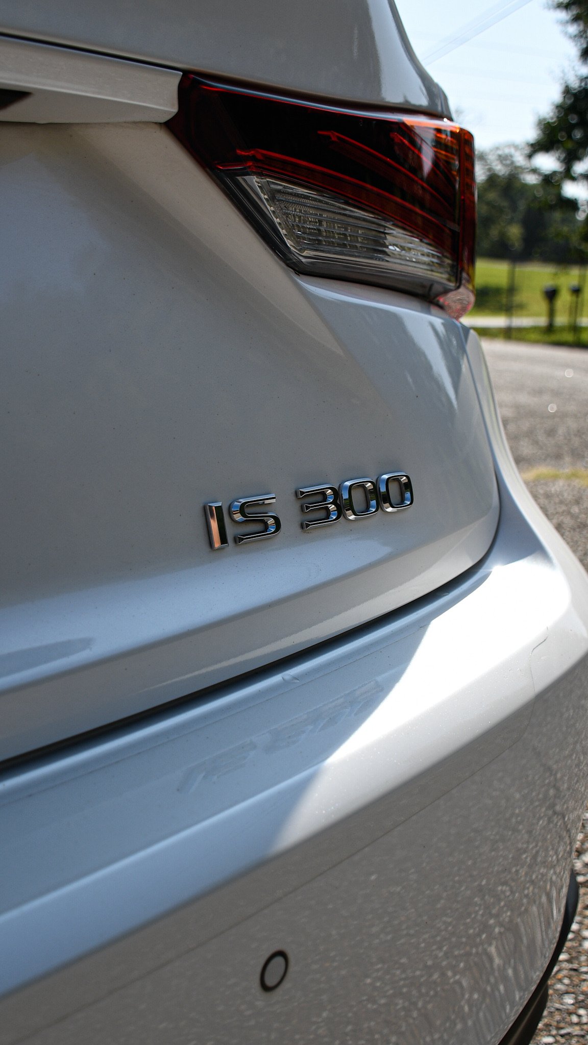 Close-up of the rear of a white vehicle showing the badge 'IS 300' and part of the tail light.