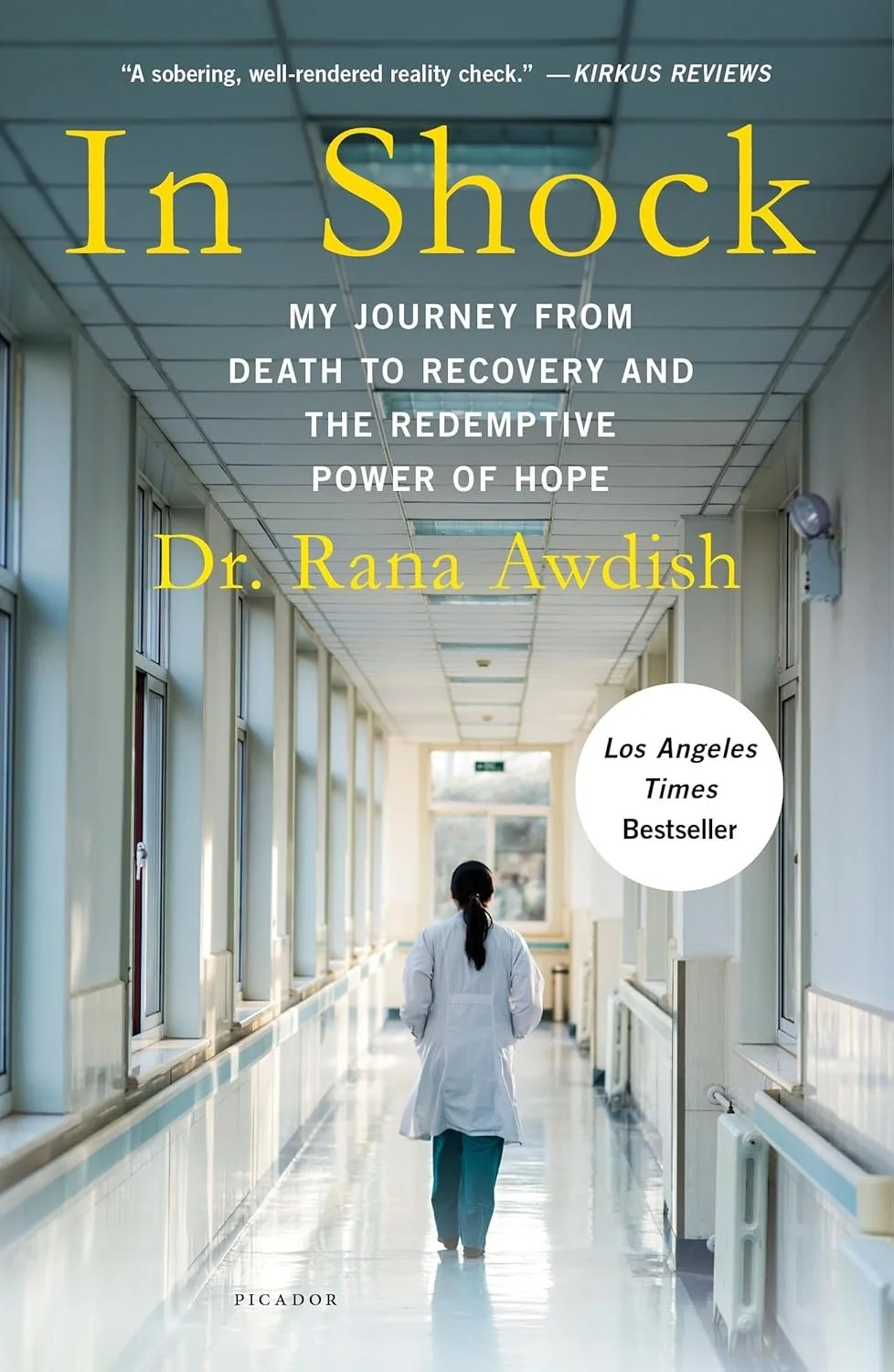 Book cover for 'In Shock: My Journey from Death to Recovery and the Redemptive Power of Hope' by Dr. Rana Awdish. The cover features a woman in medical scrubs walking down a hospital corridor with large windows on the side.