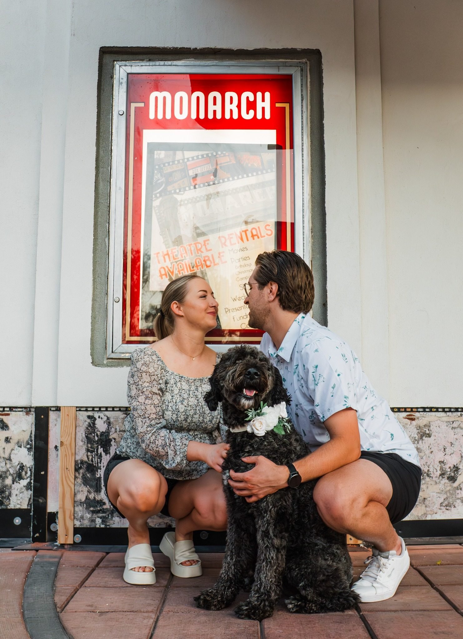 Couple with their dog outside the Monarch Theatre in Medicine Hat during an Alberta couples photography session by Kevin M Films.