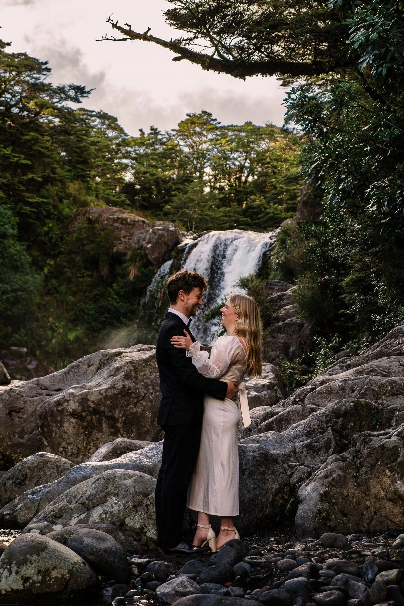 Styled elopement couple embracing near Tawhai Falls during a New Zealand elopement photography session by Kevin M Films.
